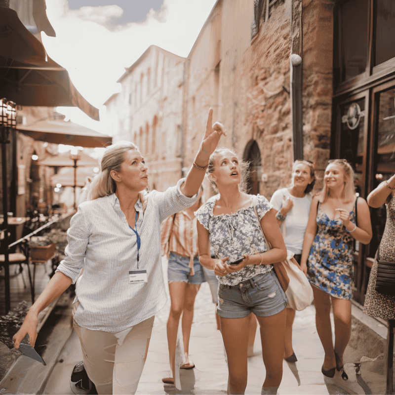 Touristen erkunden historische Stadtstraße, Reiseleiterin erklärt.