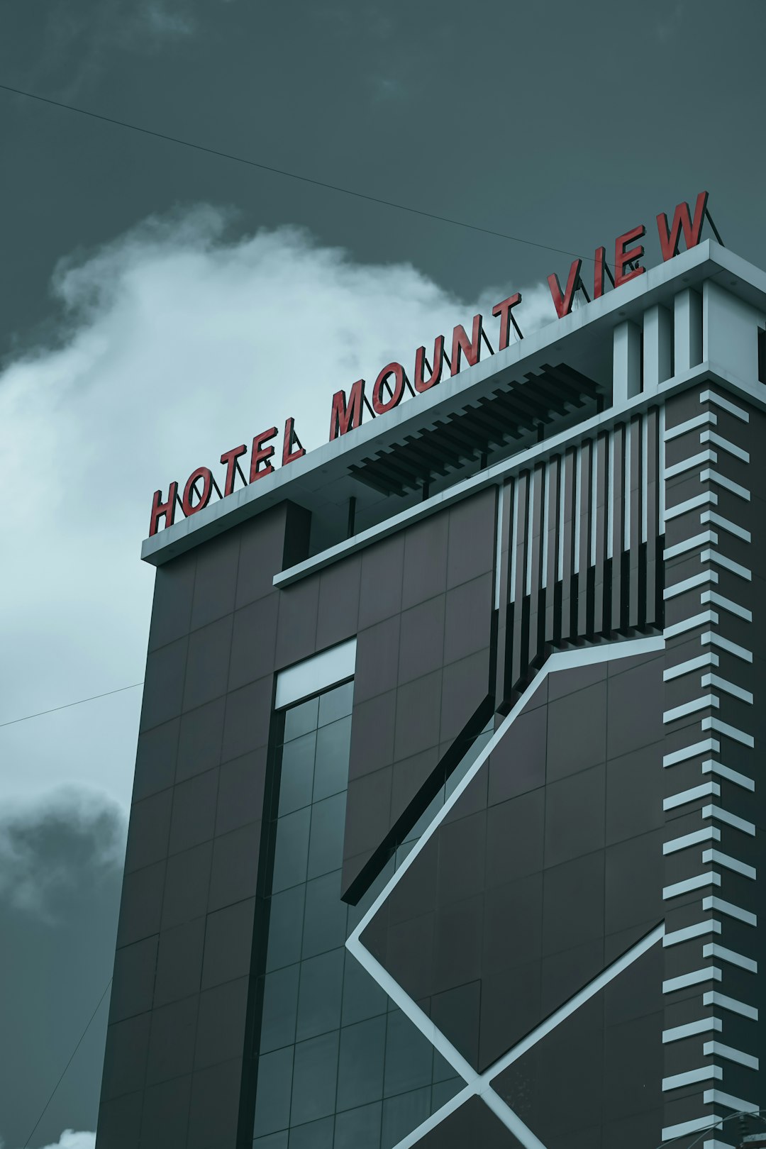 Modernes Hochhaus mit Hotelzeichen vor bewölktem Himmel.